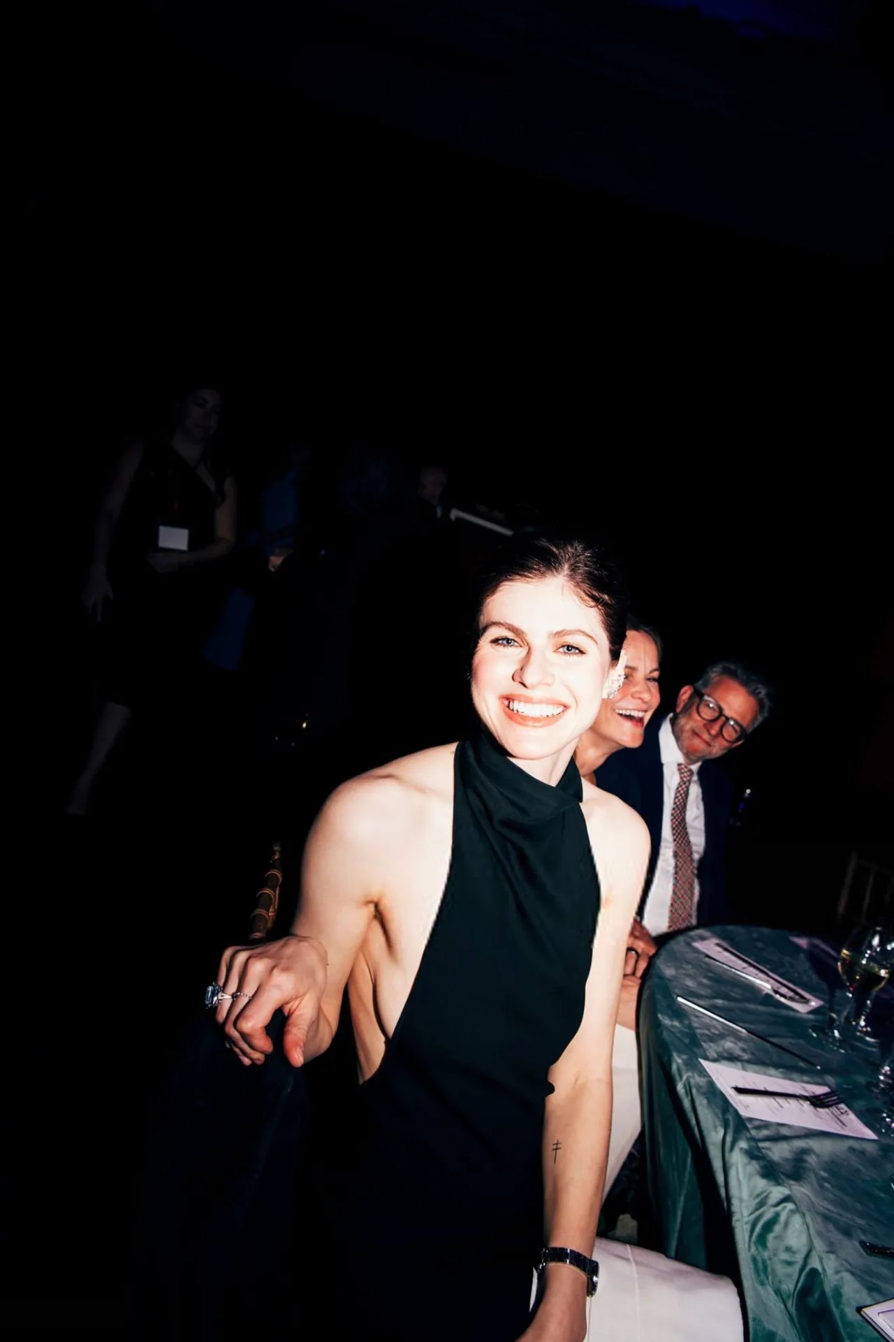 Alexandra Daddario laughing at the King's Trust gala in a black dress
