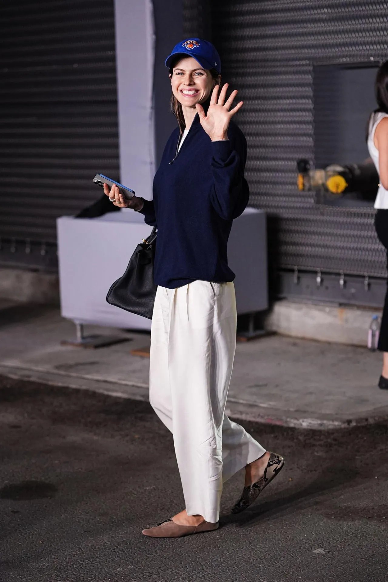 Alexandra Daddario in a Knicks cap and white trousers at the US Open, September 2026