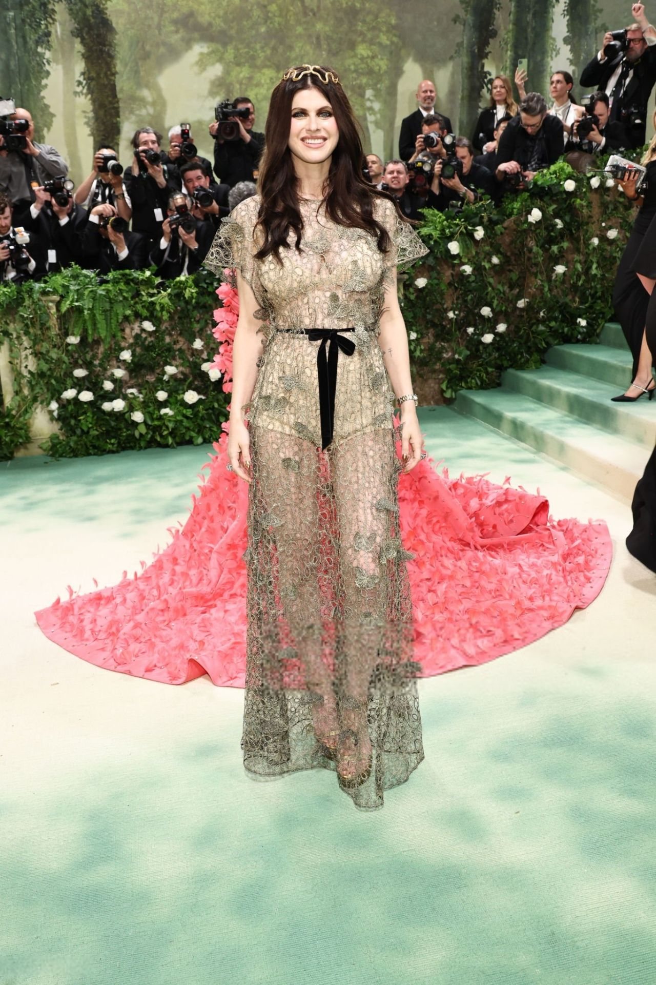 Alexandra Daddario in sheer gold lace with a pink train and a gold snake headpiece at the 2024 Met Gala