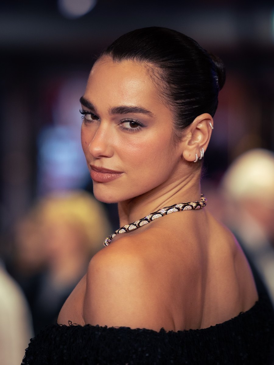 Dua Lipa looking over her shoulder in a black off-the-shoulder dress at the Rosebush Pruning premiere, Berlin International Film Festival 2026