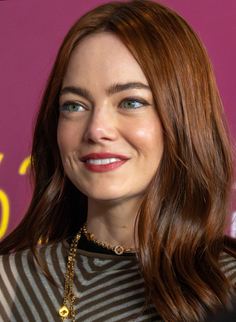 Emma Stone with long auburn hair and a gold chain necklace at the New York Film Festival, 2024