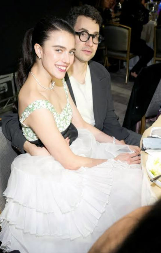 Margaret Qualley in a white ruffled gown leaning on Jack Antonoff