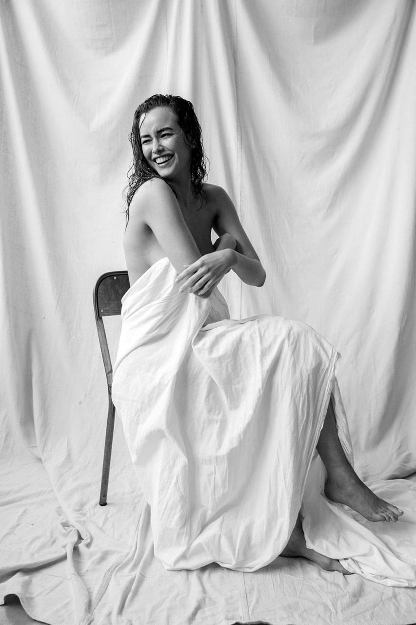 Sarah Stephens nude, seated with the sheet in her lap, laughing