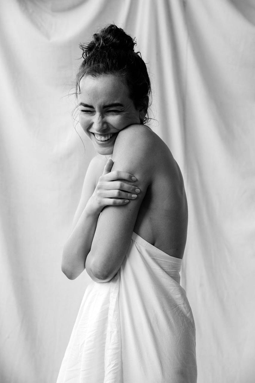 Sarah Stephens nude, the sheet around her, smiling into her shoulder