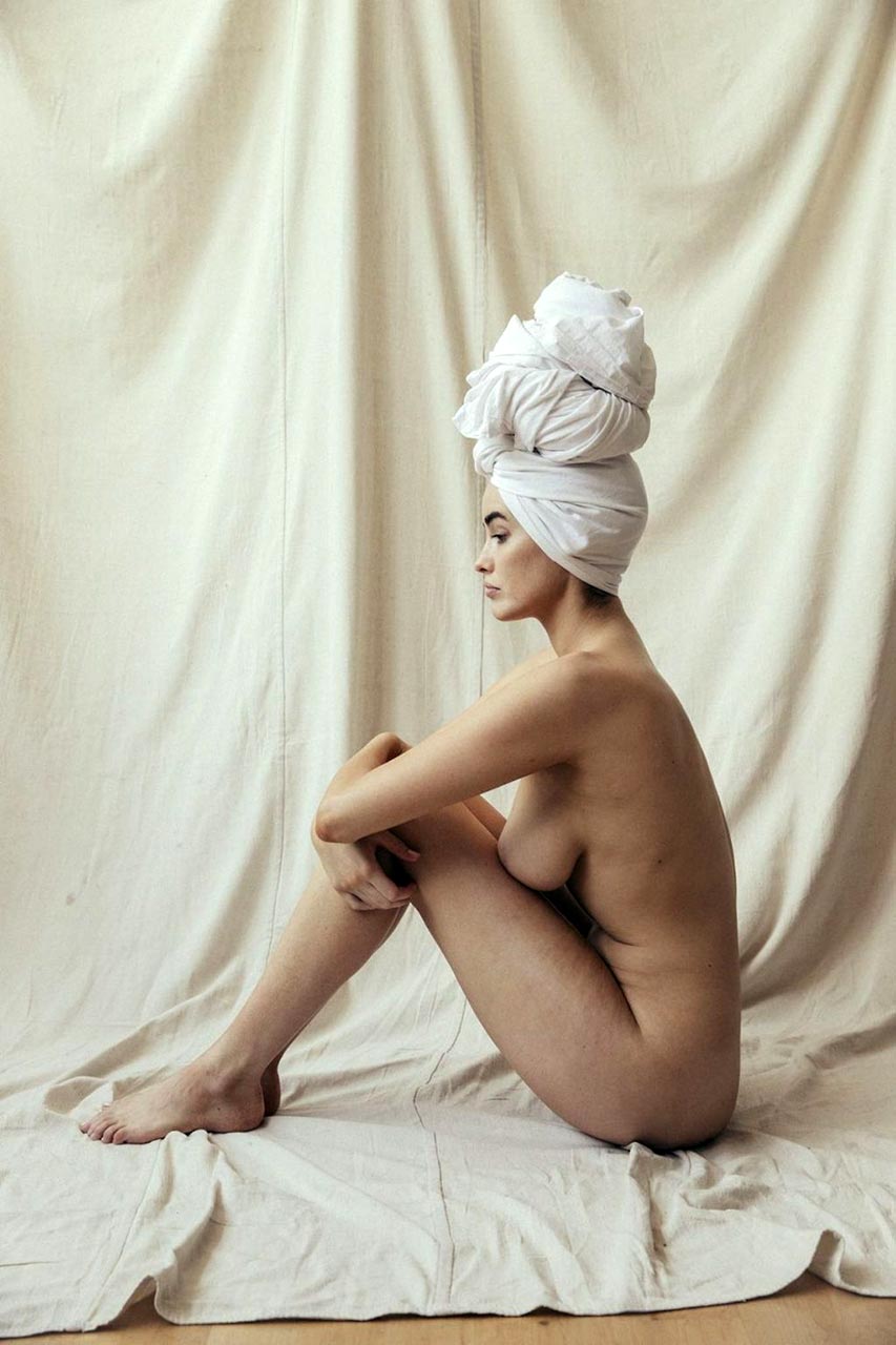 Sarah Stephens nude, white cloth wrapped on her head, seated and looking back