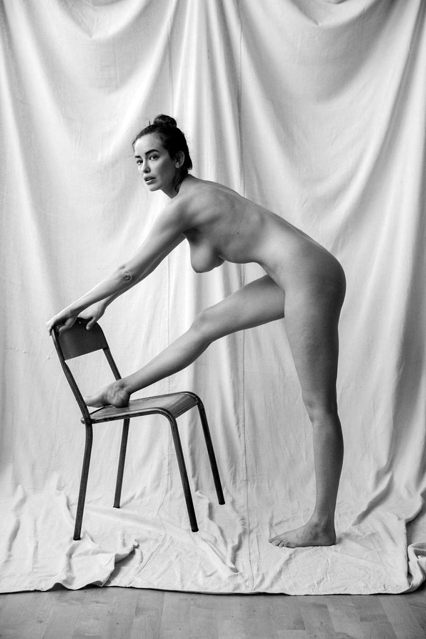 Sarah Stephens nude, one foot on the metal chair, looking back over her shoulder