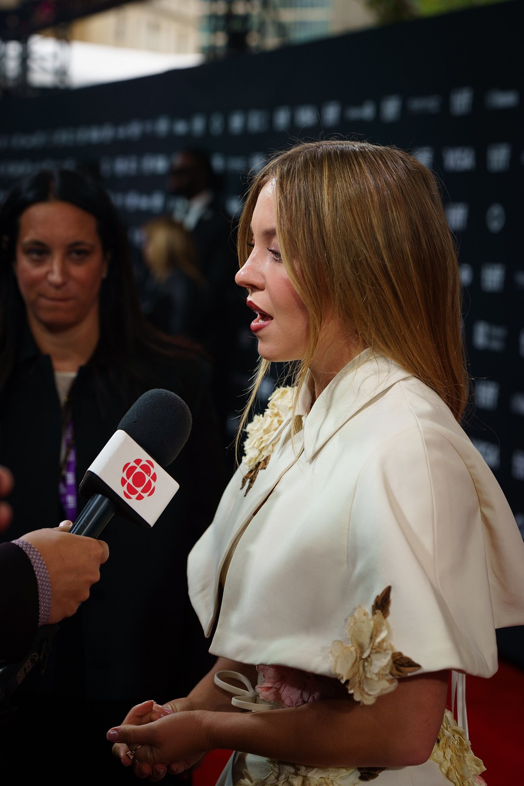Sydney Sweeney in a cream ruffled jacket being interviewed on the red carpet at the Toronto International Film Festival, 2024